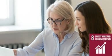 Senior and junior professionals collaborating at a laptop in a modern office